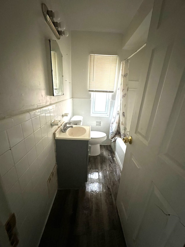 full bathroom featuring wood-type flooring, tile walls, vanity, toilet, and shower / bath combo with shower curtain