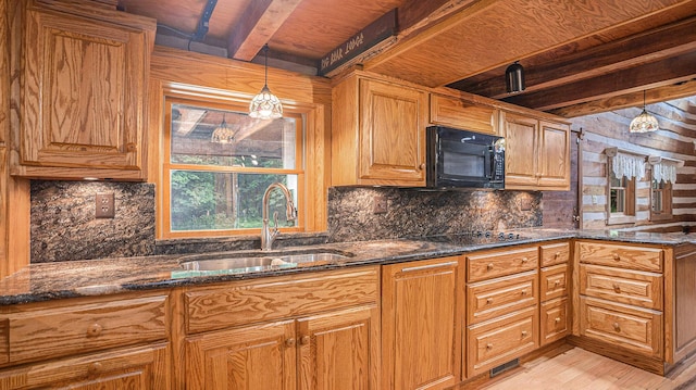 kitchen featuring pendant lighting, sink, dark stone countertops, black appliances, and light hardwood / wood-style floors