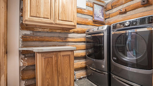 washroom featuring separate washer and dryer, log walls, and cabinets