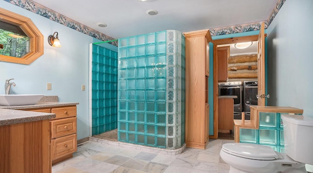 bathroom featuring vanity, toilet, washing machine and clothes dryer, and a tile shower