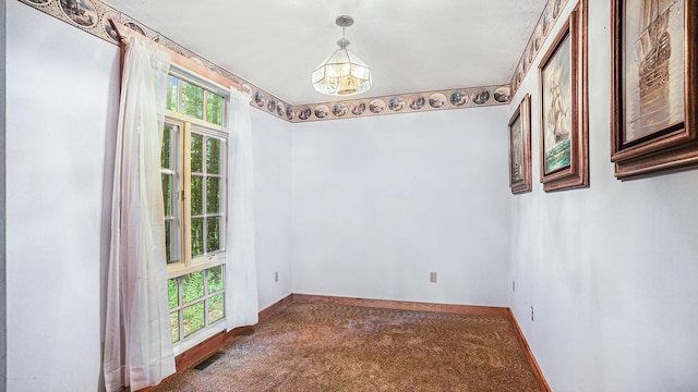 unfurnished dining area featuring a chandelier and carpet