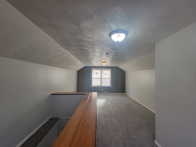 bonus room featuring a textured ceiling, carpet, and lofted ceiling