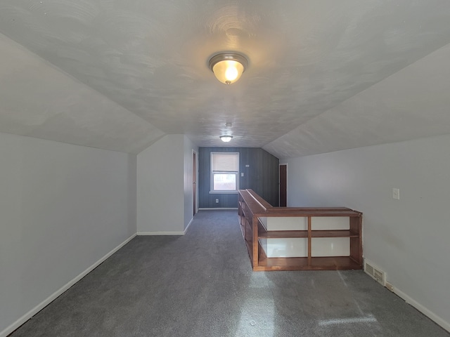 additional living space with dark carpet and lofted ceiling