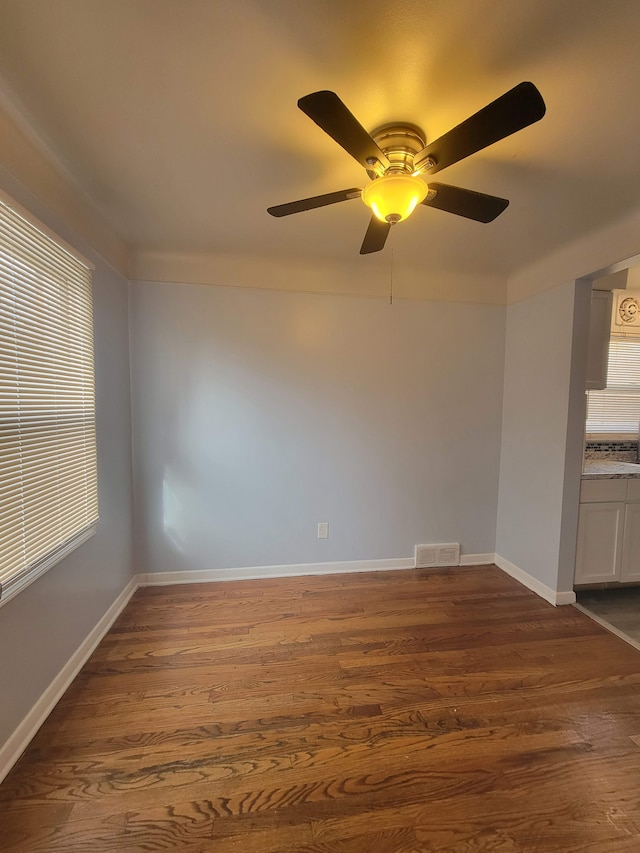 empty room featuring dark hardwood / wood-style flooring, plenty of natural light, and ceiling fan