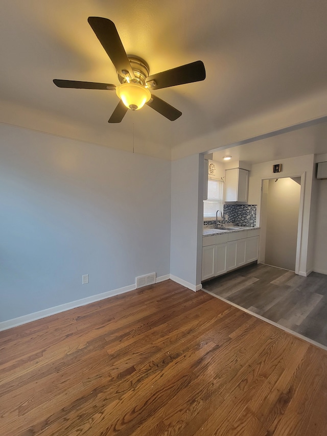 unfurnished living room with ceiling fan, sink, and dark wood-type flooring