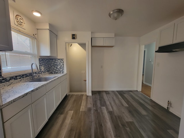 kitchen with tasteful backsplash, light stone counters, sink, white cabinets, and dark hardwood / wood-style floors