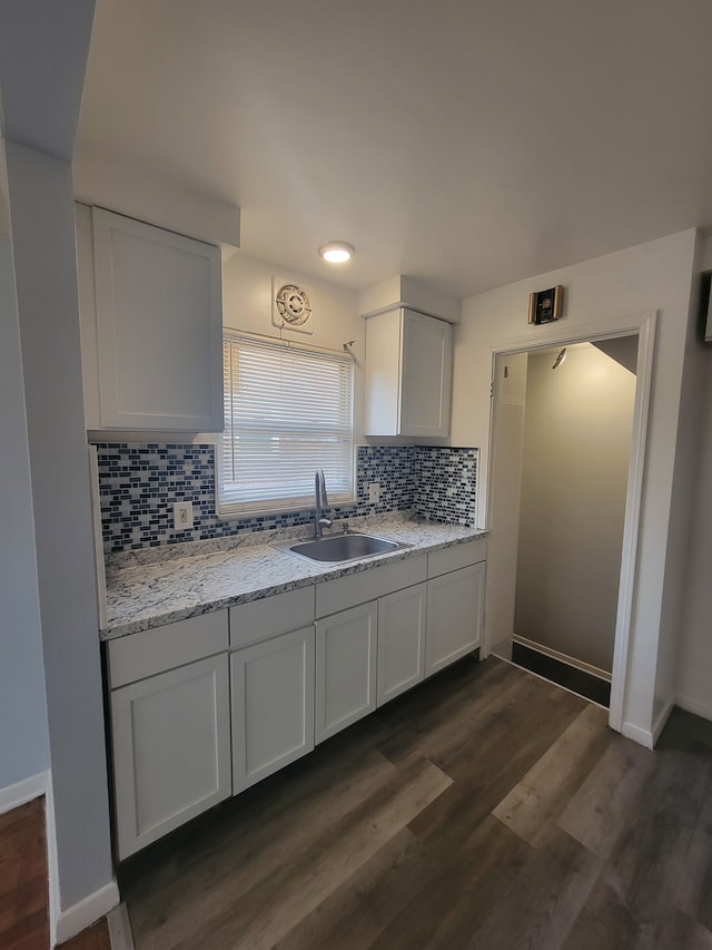 kitchen with dark hardwood / wood-style flooring, backsplash, light stone counters, sink, and white cabinets