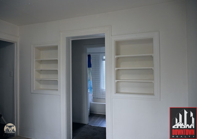 corridor with dark hardwood / wood-style flooring and built in features