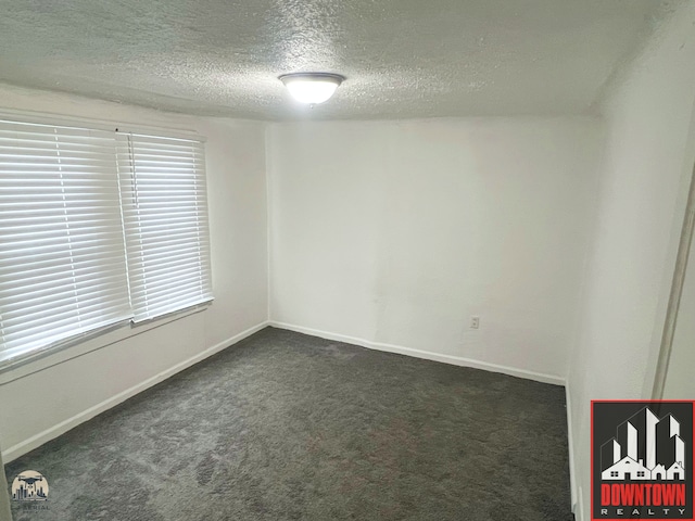 unfurnished room with dark carpet and a textured ceiling