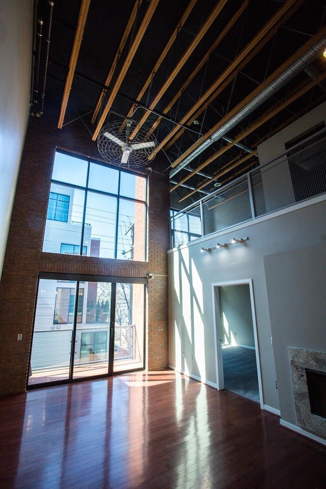 unfurnished living room with wood-type flooring, a towering ceiling, and a premium fireplace