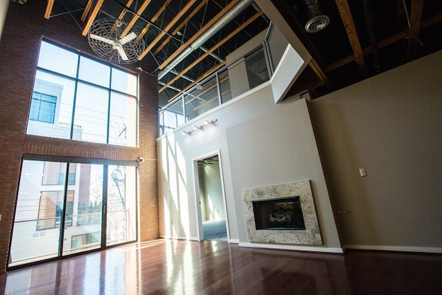 unfurnished living room featuring a high end fireplace, a high ceiling, a notable chandelier, and wood-type flooring