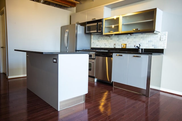 kitchen with decorative backsplash, appliances with stainless steel finishes, dark hardwood / wood-style flooring, sink, and white cabinetry