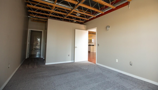 spare room featuring dark colored carpet