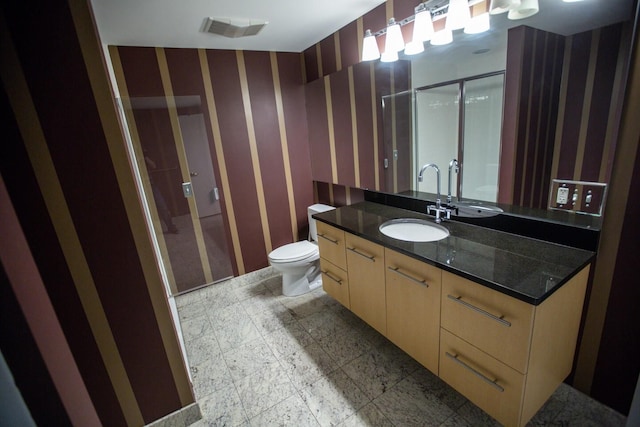 bathroom with a shower with door, vanity, and toilet