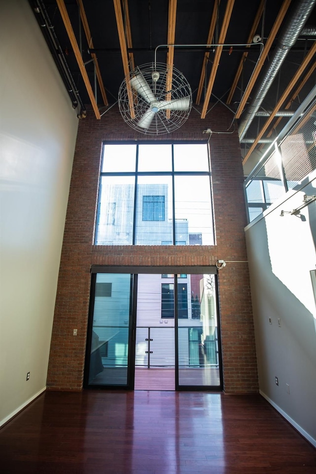 interior space with a towering ceiling and dark wood-type flooring