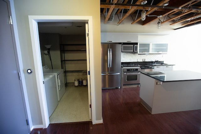 kitchen with appliances with stainless steel finishes, sink, separate washer and dryer, dark hardwood / wood-style floors, and white cabinetry