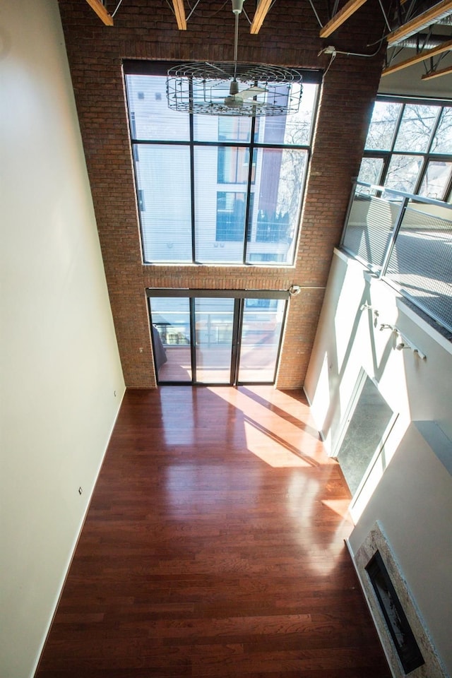 interior space featuring plenty of natural light, ceiling fan, wood-type flooring, and a towering ceiling