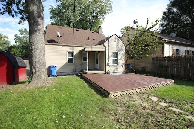 rear view of house featuring a wooden deck, a yard, and a storage shed