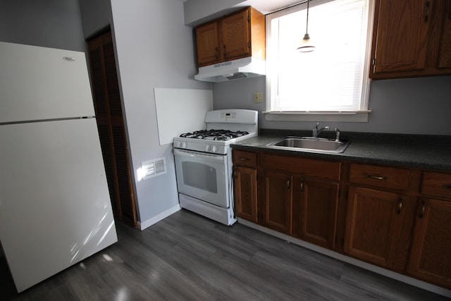 kitchen with hanging light fixtures, sink, dark wood-type flooring, and white appliances