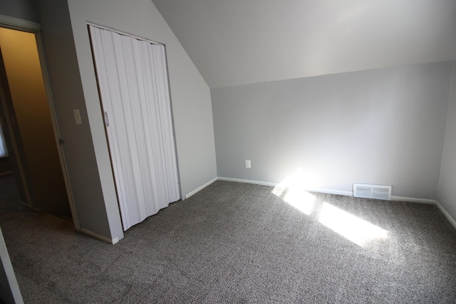 additional living space featuring vaulted ceiling and dark carpet