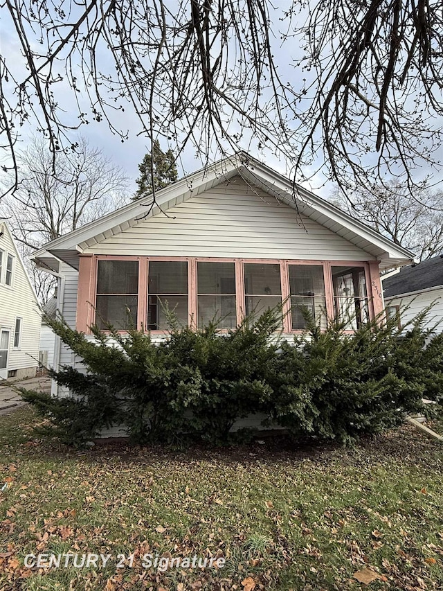 view of home's exterior with a sunroom and a lawn