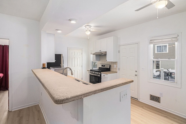 kitchen with kitchen peninsula, stainless steel appliances, sink, light hardwood / wood-style flooring, and white cabinets