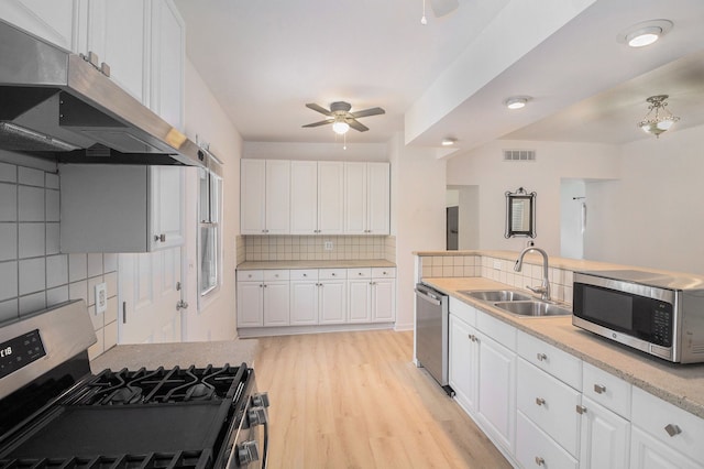 kitchen with sink, backsplash, appliances with stainless steel finishes, white cabinets, and light wood-type flooring