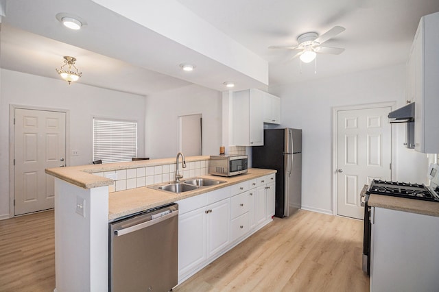 kitchen with kitchen peninsula, light wood-type flooring, stainless steel appliances, sink, and white cabinets