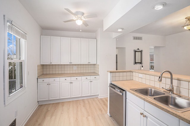 kitchen with white cabinets, sink, light hardwood / wood-style flooring, stainless steel dishwasher, and tasteful backsplash