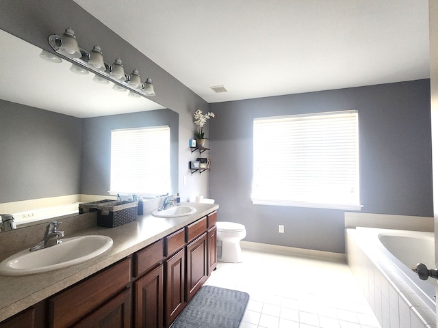 bathroom with tile patterned floors, vanity, toilet, and tiled bath