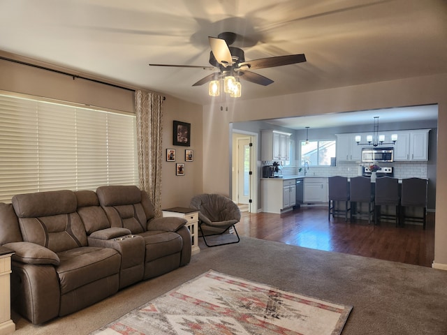 living room with ceiling fan with notable chandelier and dark wood-type flooring