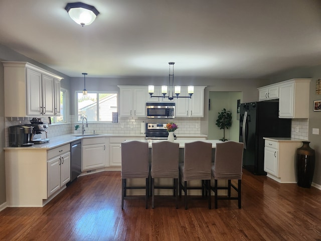 kitchen with decorative light fixtures, a center island, stainless steel appliances, and dark hardwood / wood-style floors