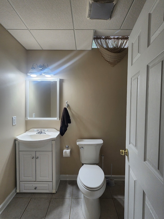 bathroom featuring tile patterned floors, a paneled ceiling, vanity, and toilet