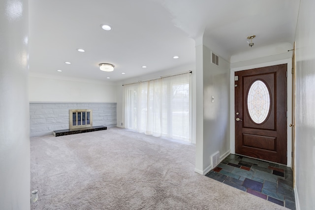 entrance foyer with dark carpet, a wealth of natural light, and a stone fireplace