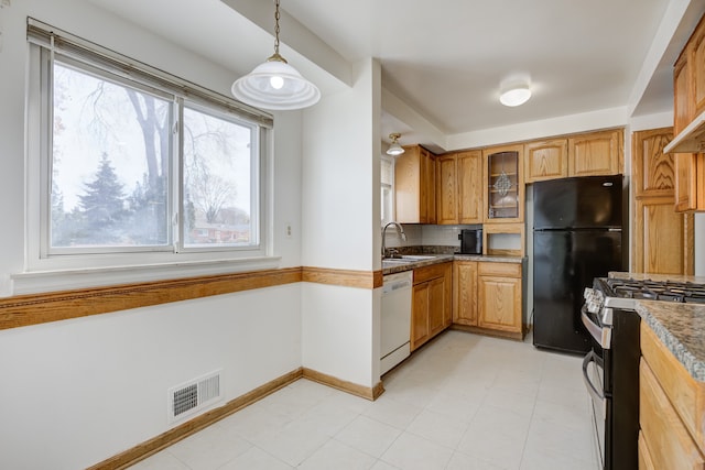 kitchen with dishwasher, gas stove, black fridge, and a healthy amount of sunlight