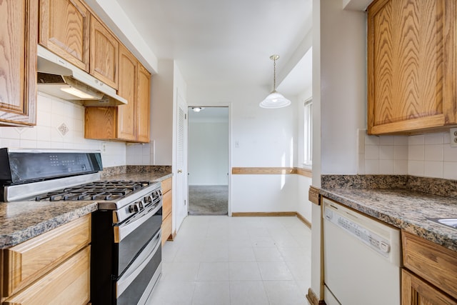 kitchen featuring stainless steel gas range oven, white dishwasher, dark stone counters, decorative light fixtures, and light tile patterned floors