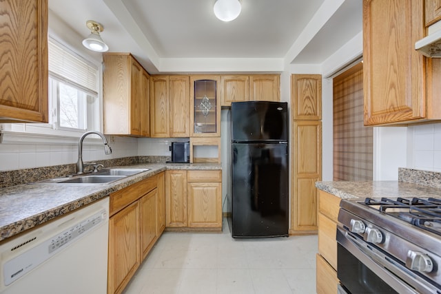 kitchen featuring backsplash, black fridge, sink, and white dishwasher