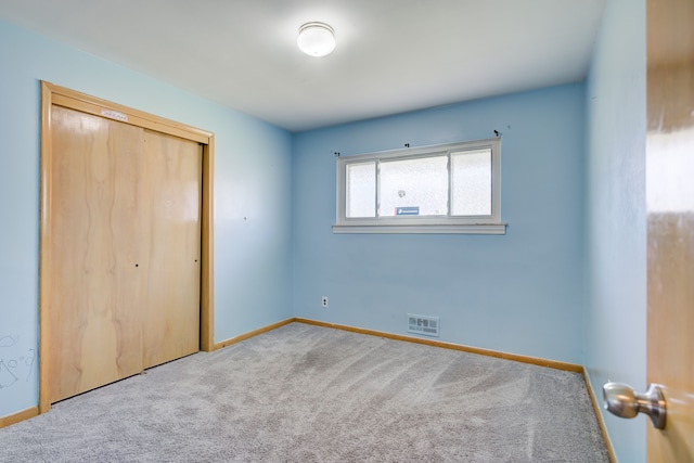 unfurnished bedroom featuring light carpet and a closet