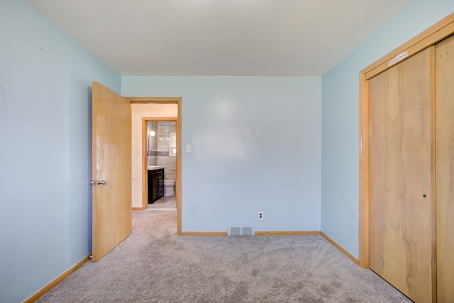 unfurnished bedroom with light carpet and a closet