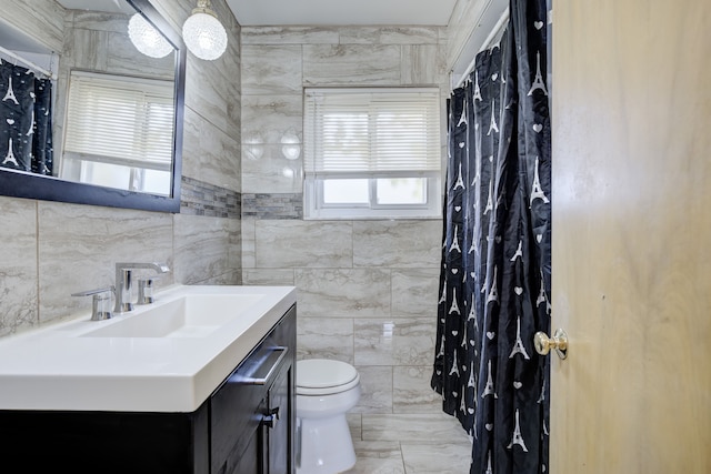 bathroom featuring vanity, toilet, and tile walls