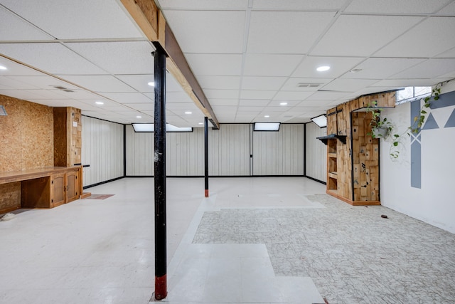 basement with wooden walls and a drop ceiling