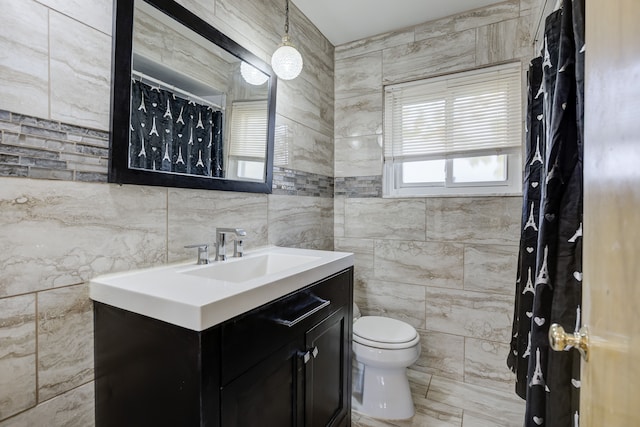 bathroom featuring vanity, toilet, and tile walls