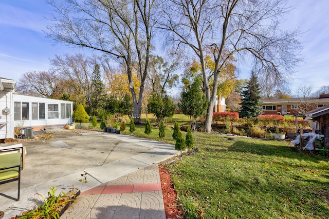 view of yard with central air condition unit, a patio area, and a sunroom