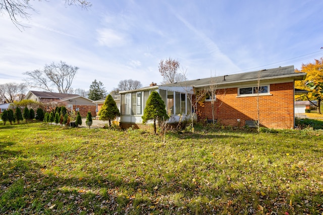 rear view of property featuring a yard and a sunroom