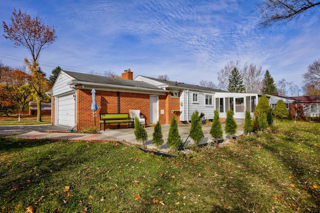 back of house with a garage, a lawn, and a sunroom