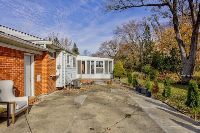 view of patio featuring central air condition unit and a sunroom