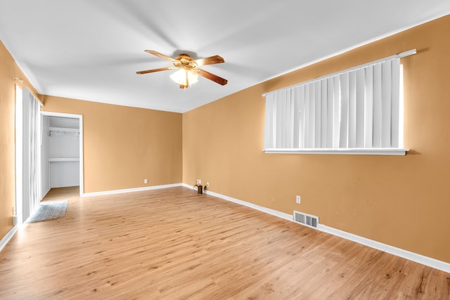 unfurnished bedroom featuring a closet, ceiling fan, light hardwood / wood-style flooring, and a spacious closet