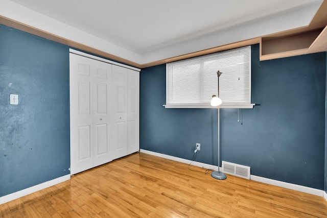 unfurnished bedroom with wood-type flooring and a closet