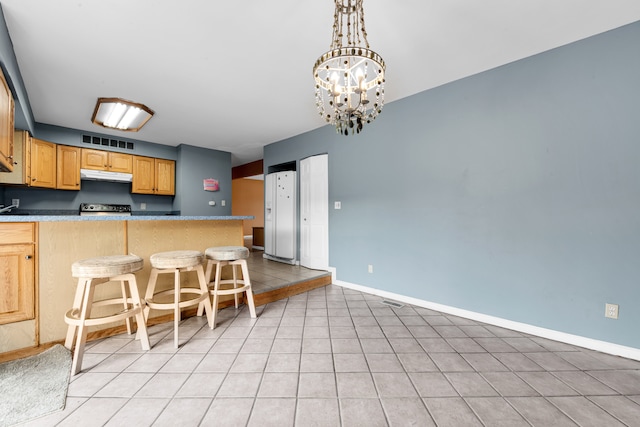 kitchen featuring an inviting chandelier, kitchen peninsula, light tile patterned flooring, a kitchen bar, and range