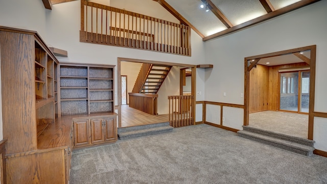 unfurnished living room with carpet floors and high vaulted ceiling